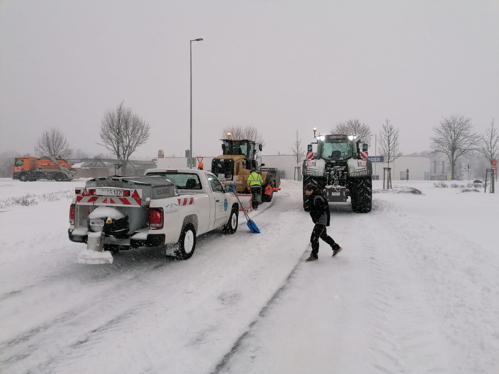 Winterschutzmaßnahmen -Mitarbeiter streuen Streusalz auf die Straße und entfernen den Schnee von der Straße